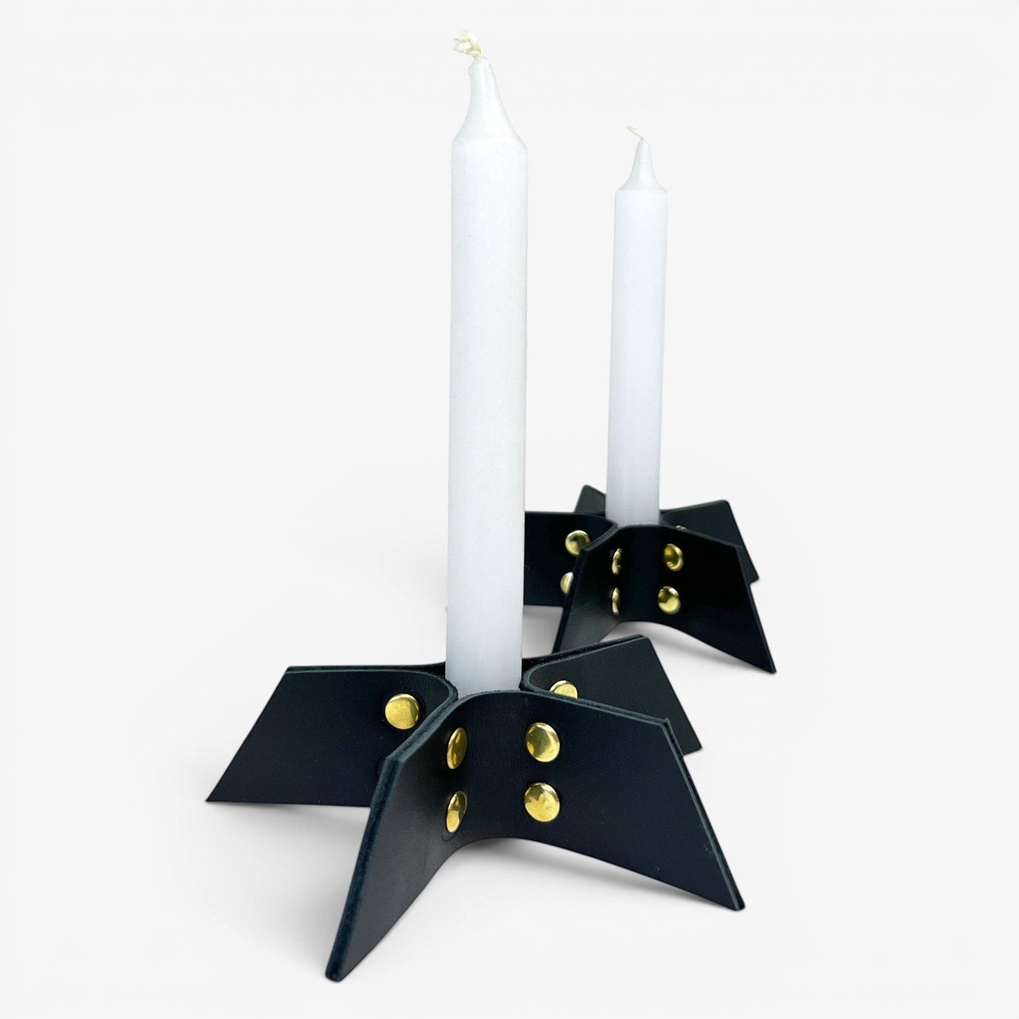 Pache black leather candle holder set with gold rivets, minimalist design, holding white taper candles.