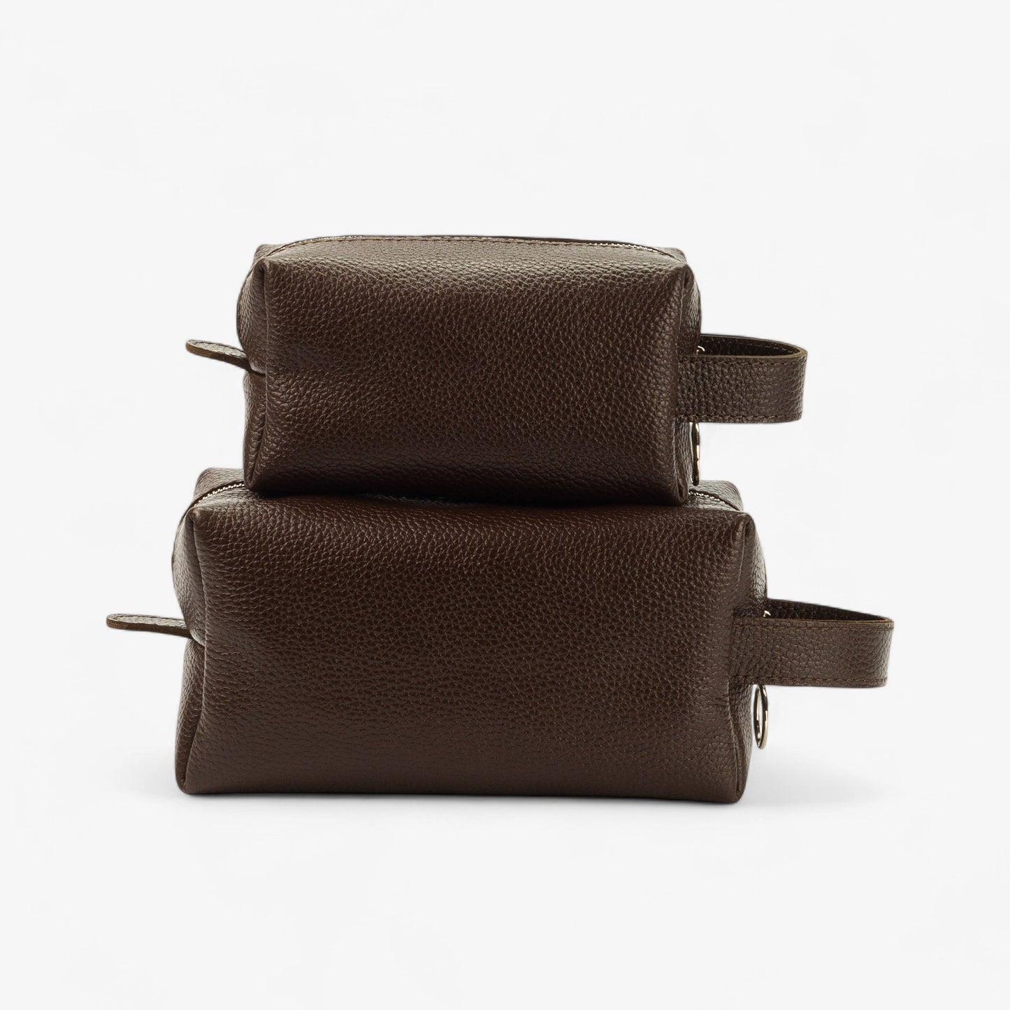Two brown leather toiletry bags stacked on a white background