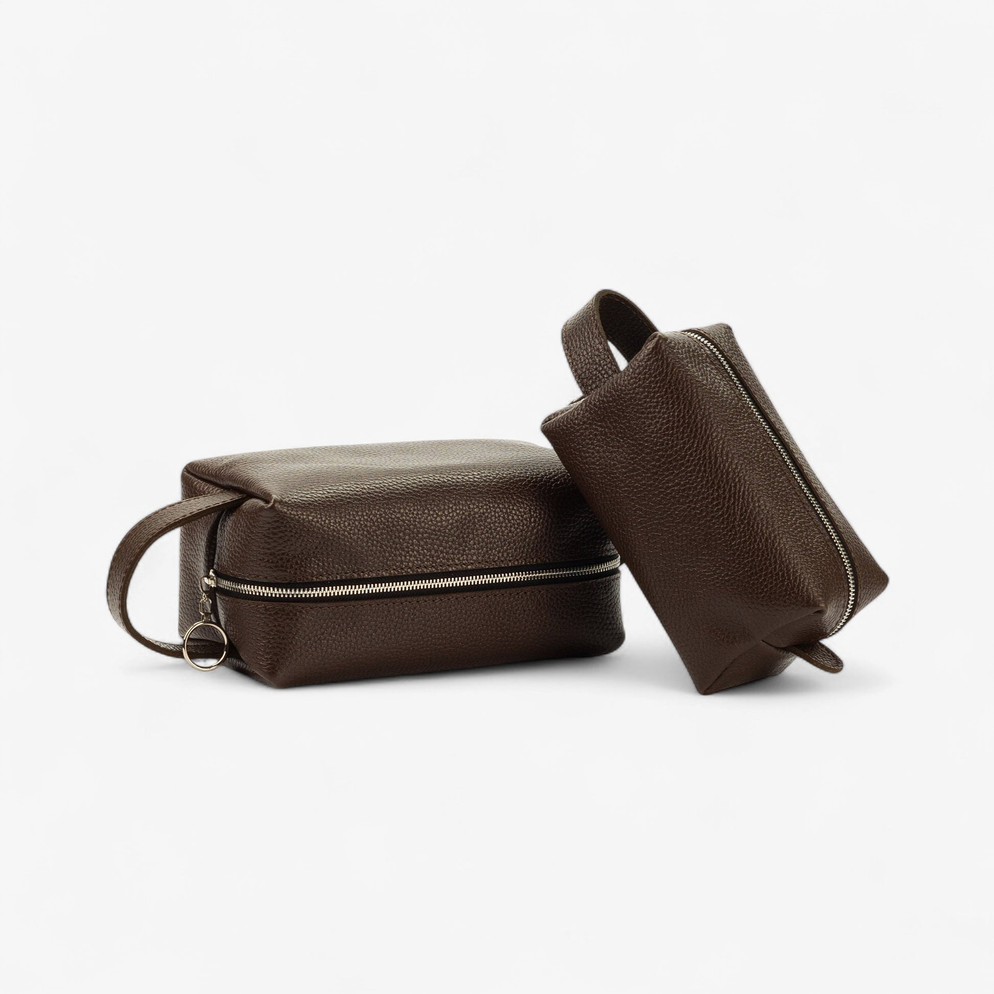 Two brown leather toiletry bags on a white background