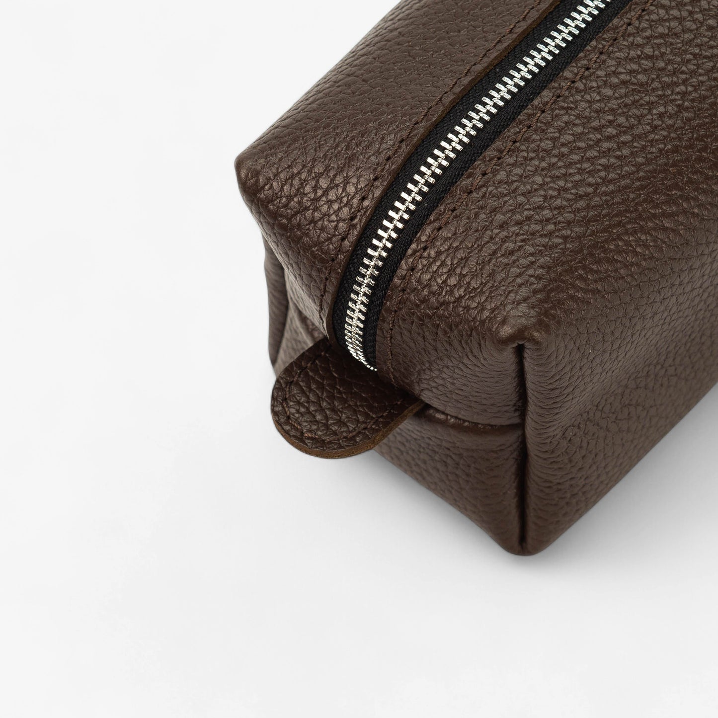 Brown leather toiletry bag with a zipper on a white background