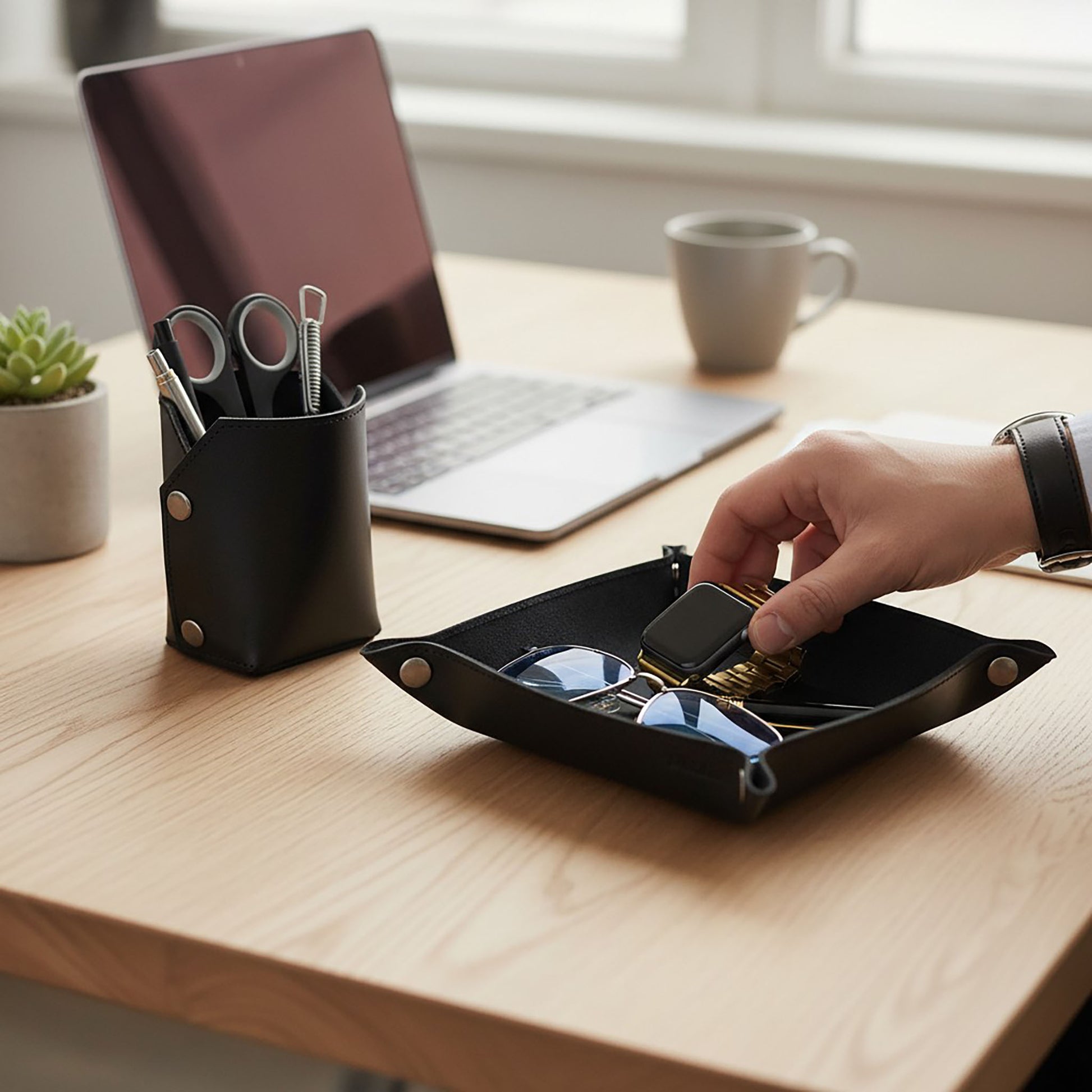 Pache black leather desk organizer set with a pen holder and a tray holding sunglasses and a watch.