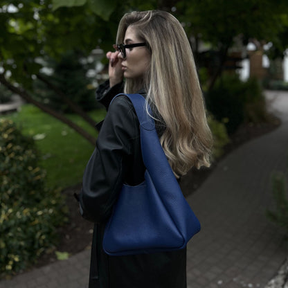 Pache blue pebbled leather hobo bag worn by a woman with blonde hair and sunglasses