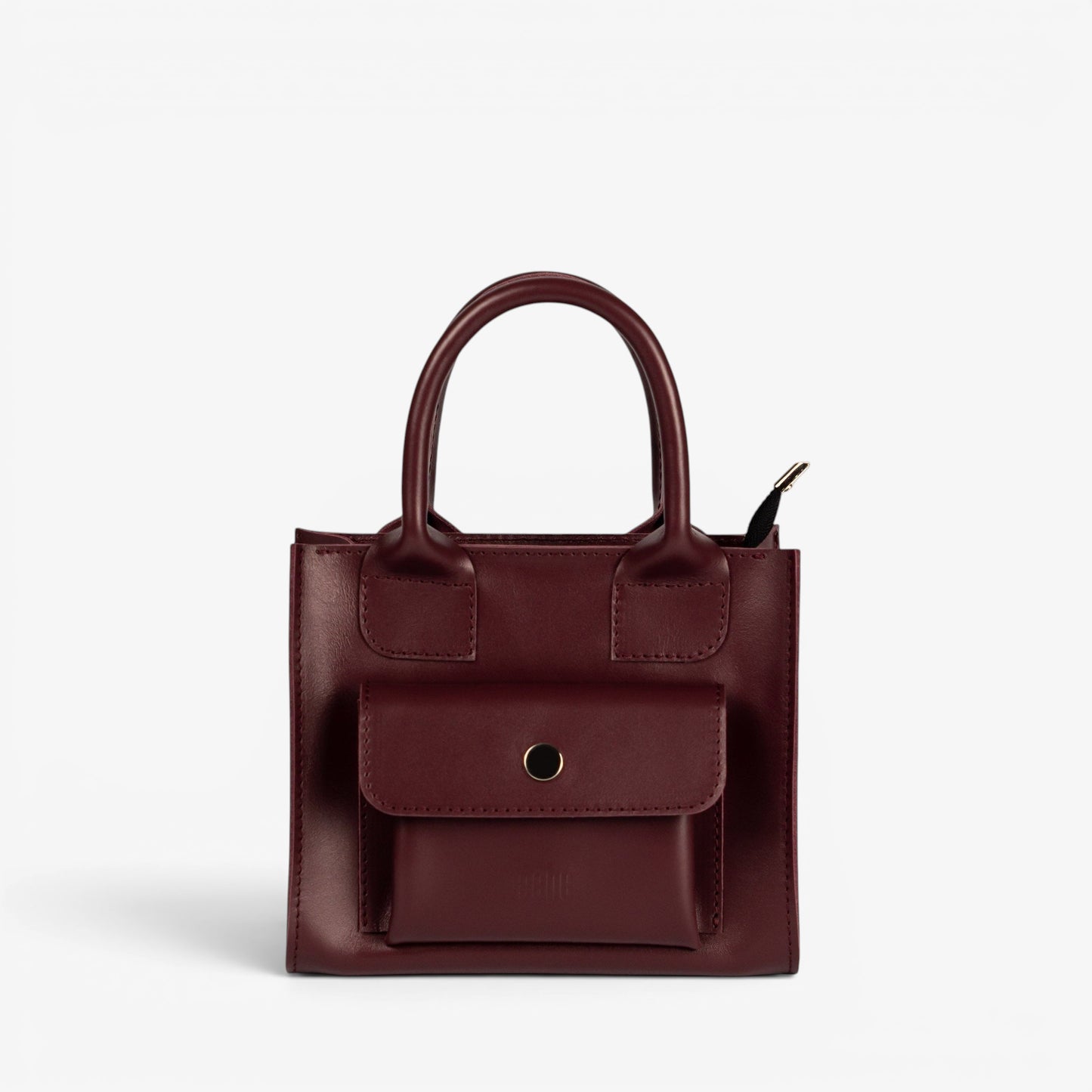 Pache Sigil mini tote bag in deep burgundy smooth leather with a structured shape and front pocket. Adjustable strap for shoulder or crossbody wear.