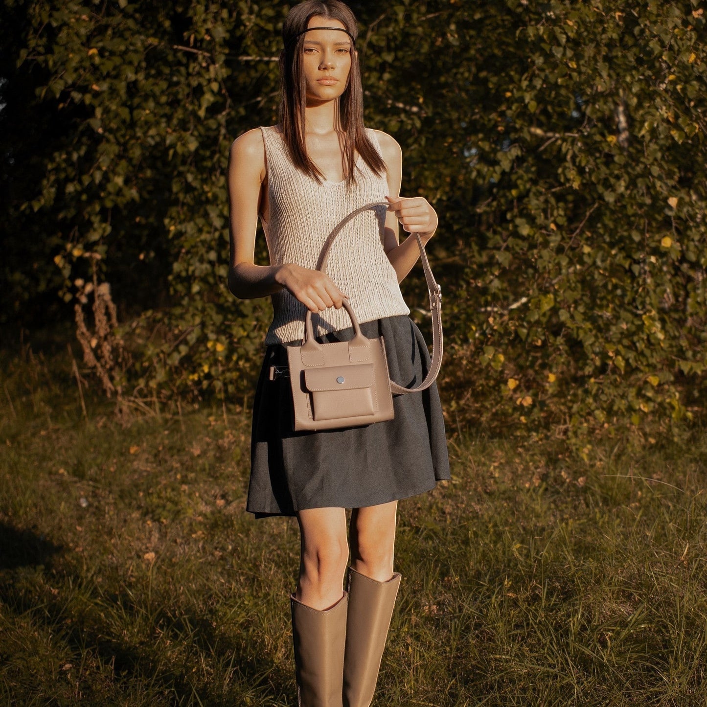 Pache gray smooth leather mini tote bag with adjustable strap, worn by a model outdoors.