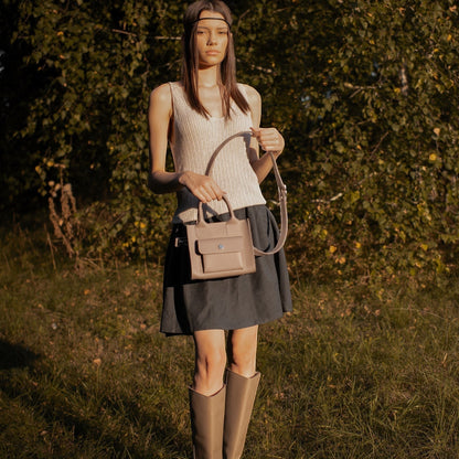 Pache gray smooth leather mini tote bag with adjustable strap, worn by a model outdoors.