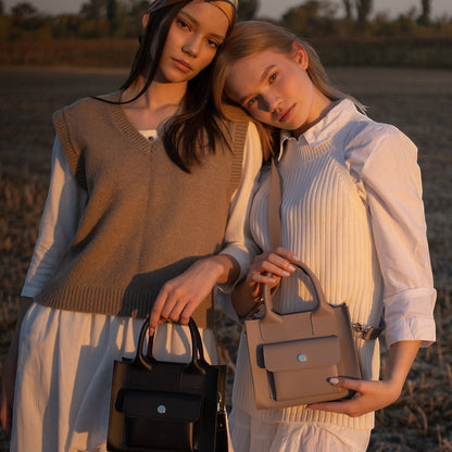 Pache gray mini tote bag made of smooth leather with a structured shape and adjustable strap, held by a woman.