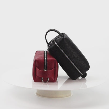 Handmade leather cosmetic bags in black and red rotating 360 degrees, showing the shape, texture, and craftsmanship from all sides.